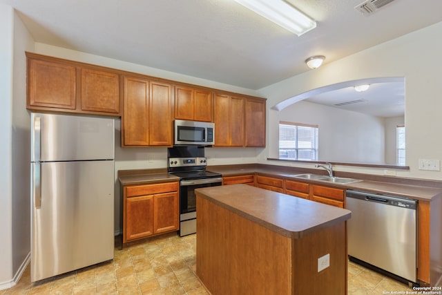 kitchen featuring stainless steel appliances, sink, kitchen peninsula, and a kitchen island