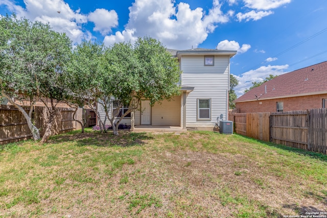 rear view of house with central air condition unit, a patio, and a yard