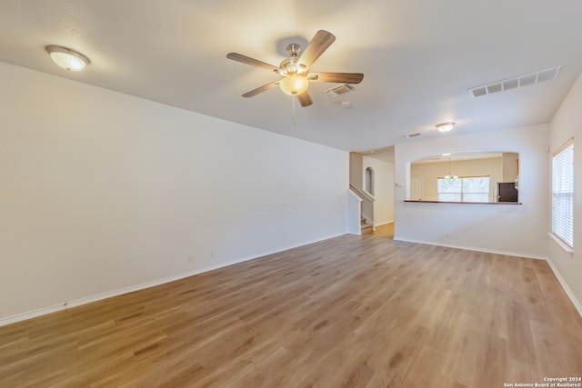 unfurnished living room featuring ceiling fan with notable chandelier and hardwood / wood-style floors