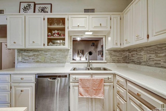 kitchen featuring tasteful backsplash, dishwasher, sink, and white cabinets