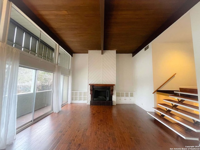 unfurnished living room with dark wood-type flooring, beam ceiling, a high ceiling, and wooden ceiling