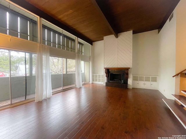 unfurnished living room with a towering ceiling, hardwood / wood-style floors, and beam ceiling