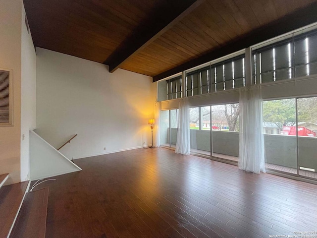 spare room featuring hardwood / wood-style floors, wood ceiling, beamed ceiling, and a towering ceiling