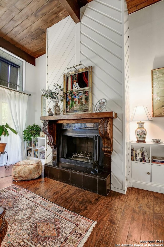 living room featuring vaulted ceiling with beams, hardwood / wood-style floors, a tile fireplace, and wooden ceiling