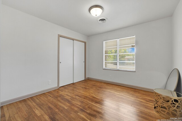 unfurnished bedroom featuring a closet and hardwood / wood-style flooring