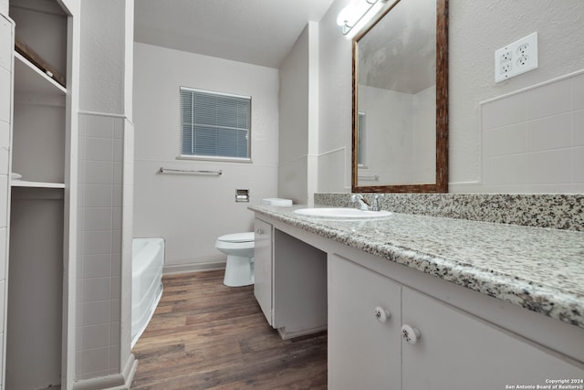 bathroom featuring hardwood / wood-style floors, toilet, vanity, and a bath