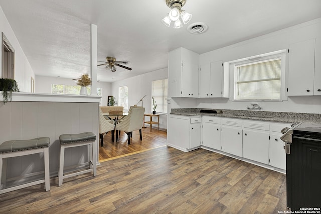 kitchen with light stone countertops, dark wood-type flooring, and white cabinetry