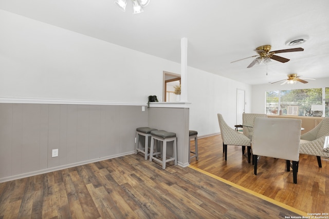 dining room featuring wood walls, wood-type flooring, and ceiling fan