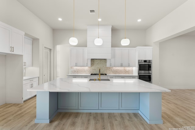 kitchen featuring white cabinets, hanging light fixtures, light hardwood / wood-style flooring, appliances with stainless steel finishes, and light stone countertops