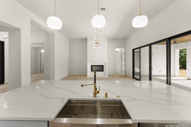 kitchen with hanging light fixtures, sink, and light hardwood / wood-style flooring