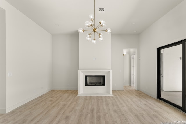 unfurnished living room with light wood-type flooring and a chandelier