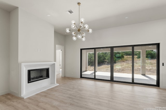 unfurnished living room featuring an inviting chandelier and light hardwood / wood-style floors