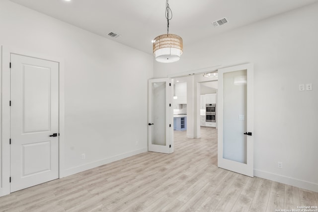 spare room featuring french doors and light hardwood / wood-style flooring