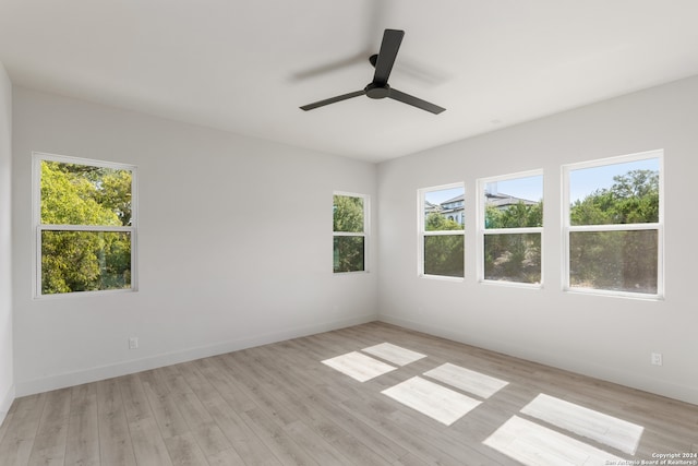 empty room featuring ceiling fan, light wood-type flooring, and a healthy amount of sunlight