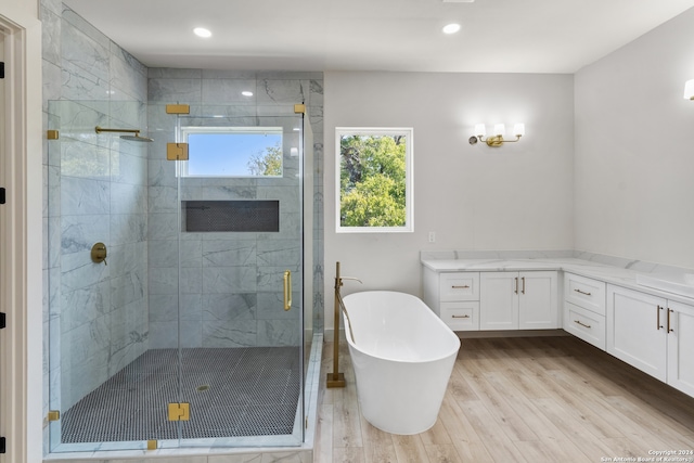 bathroom with wood-type flooring, vanity, and independent shower and bath