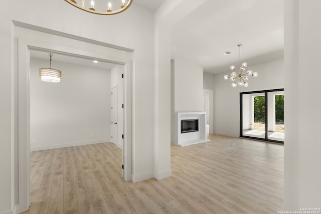 unfurnished living room featuring a chandelier and light hardwood / wood-style flooring