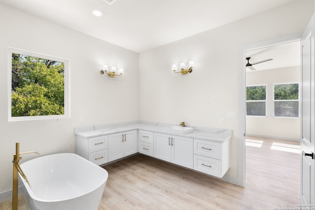 bathroom with wood-type flooring, vanity, a tub to relax in, and ceiling fan