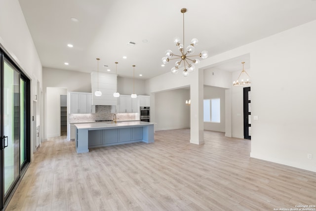 kitchen featuring hanging light fixtures, light hardwood / wood-style floors, a spacious island, and double oven