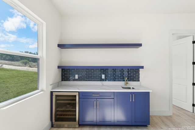 bar featuring plenty of natural light, wine cooler, decorative backsplash, and light hardwood / wood-style flooring