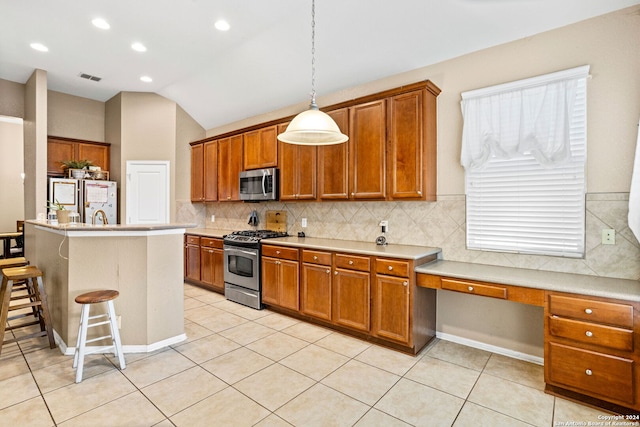 kitchen featuring a kitchen breakfast bar, a center island with sink, vaulted ceiling, stainless steel appliances, and hanging light fixtures