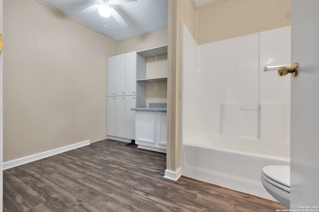 bathroom featuring ceiling fan, hardwood / wood-style floors, bathtub / shower combination, toilet, and a textured ceiling