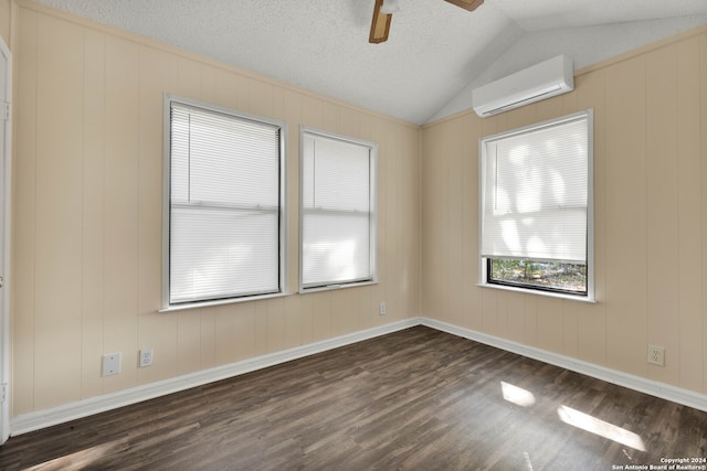 unfurnished room featuring lofted ceiling, a wall mounted air conditioner, dark hardwood / wood-style floors, and a textured ceiling