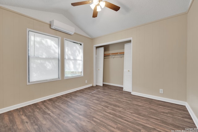 unfurnished bedroom with ceiling fan, lofted ceiling, a wall mounted AC, a textured ceiling, and dark hardwood / wood-style flooring