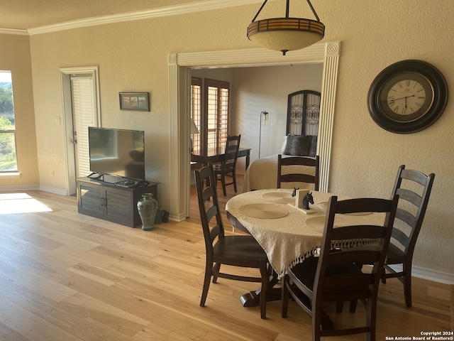 dining space with plenty of natural light, crown molding, and light wood-type flooring