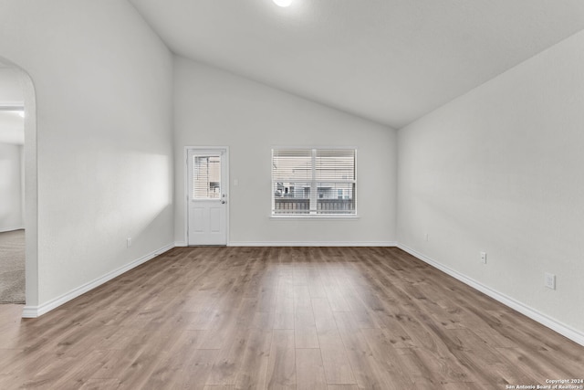 empty room with light wood-type flooring and high vaulted ceiling