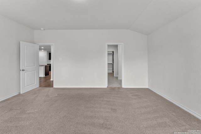 spare room featuring carpet flooring and vaulted ceiling