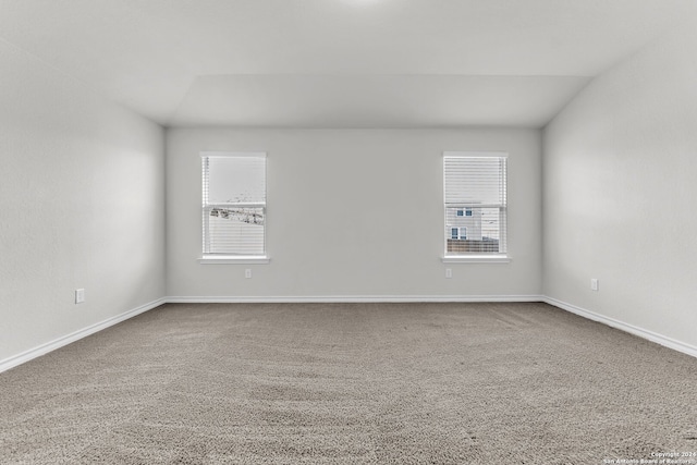 carpeted empty room with vaulted ceiling and plenty of natural light