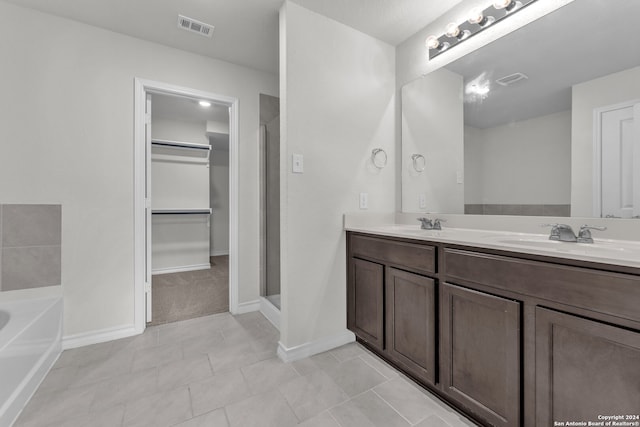 bathroom featuring tile patterned flooring, vanity, and a tub