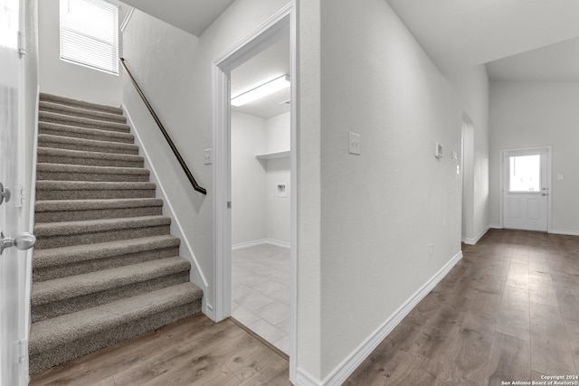 staircase with lofted ceiling and wood-type flooring