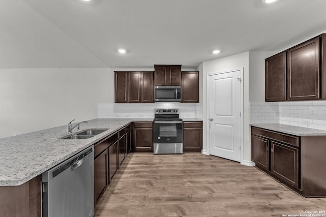 kitchen with stainless steel appliances, light wood-type flooring, decorative backsplash, sink, and kitchen peninsula