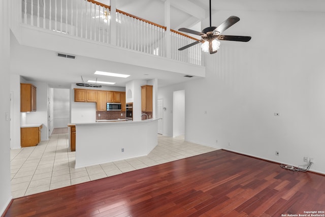 kitchen with ceiling fan, beam ceiling, light hardwood / wood-style floors, and high vaulted ceiling