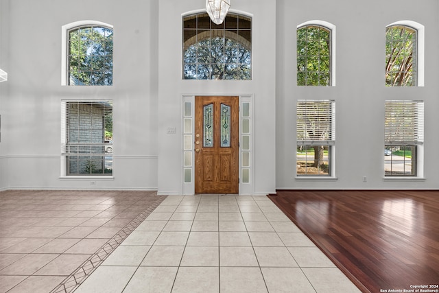 foyer featuring light hardwood / wood-style flooring, a towering ceiling, and a chandelier