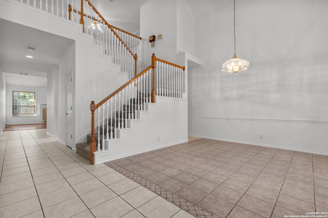 stairway featuring an inviting chandelier, baseboards, tile patterned flooring, and a towering ceiling