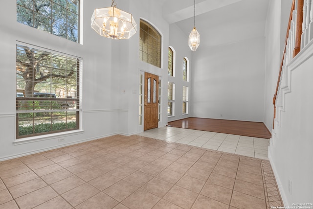 tiled foyer featuring a high ceiling and an inviting chandelier