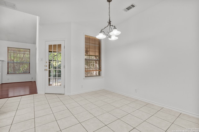 tiled empty room with a notable chandelier and vaulted ceiling