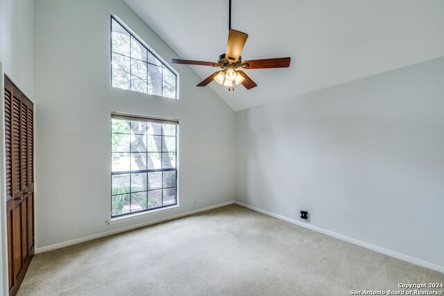 unfurnished room featuring ceiling fan, light colored carpet, and high vaulted ceiling