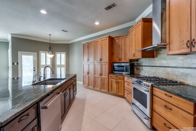 kitchen featuring sink, dark stone countertops, wall chimney range hood, crown molding, and appliances with stainless steel finishes