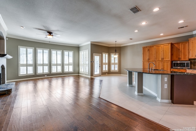 kitchen featuring ceiling fan with notable chandelier, pendant lighting, light hardwood / wood-style floors, and a wealth of natural light