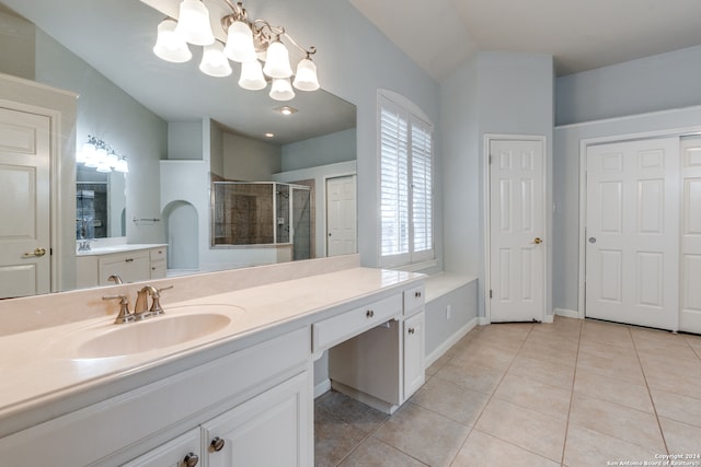 bathroom featuring an inviting chandelier, lofted ceiling, tile patterned flooring, a shower with shower door, and vanity