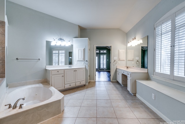 bathroom featuring a tub to relax in, vanity, vaulted ceiling, and tile patterned floors