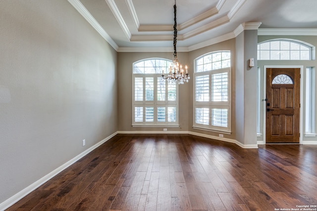 entrance foyer featuring a notable chandelier, dark wood-type flooring, ornamental molding, and a raised ceiling