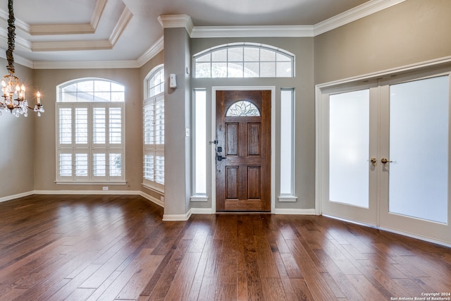 foyer featuring a raised ceiling, an inviting chandelier, crown molding, and dark hardwood / wood-style floors