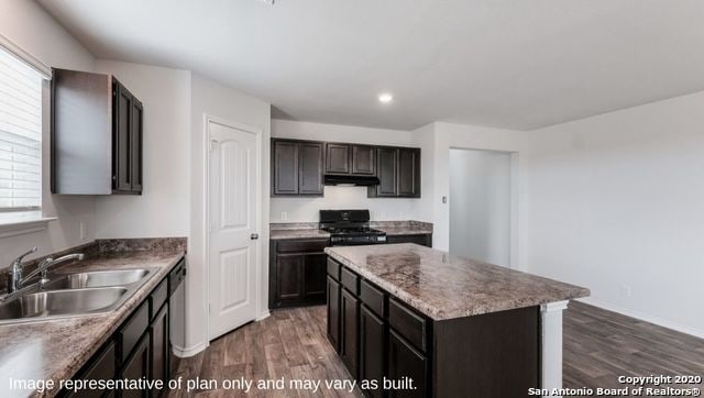 kitchen with dark wood-type flooring, black gas stove, sink, and a wealth of natural light