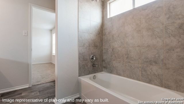 bathroom featuring hardwood / wood-style flooring and tiled shower / bath