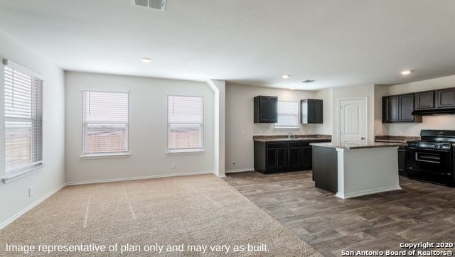 kitchen with black stove, a center island, and carpet flooring