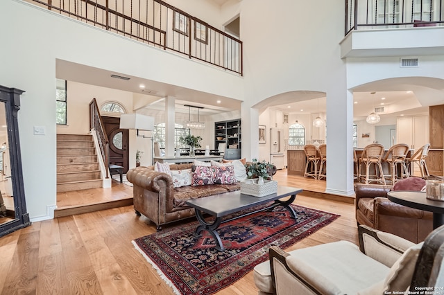 living room featuring a chandelier, light hardwood / wood-style flooring, and a towering ceiling